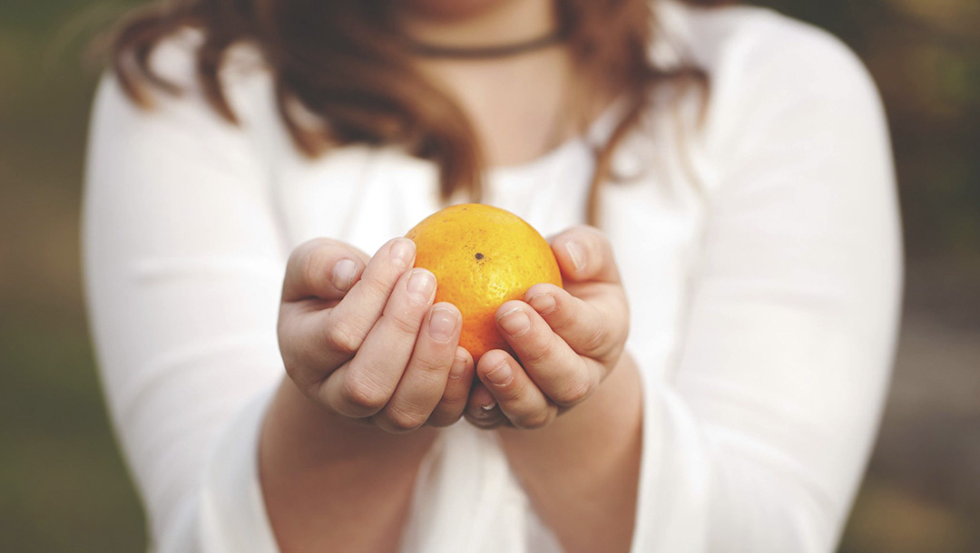 Hands holding an orange