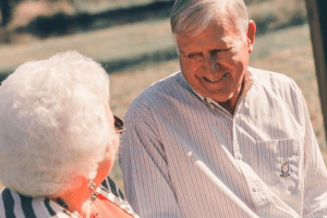 An lovely older couple sits and smiles at each other.