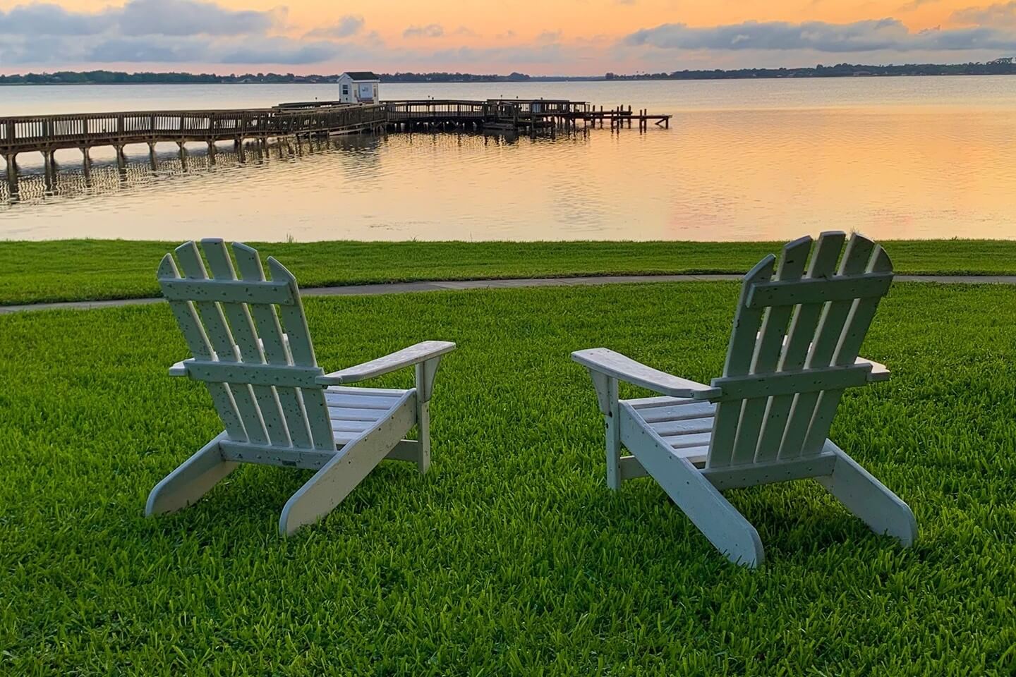 Two chairs sit on the lawn and overlook Lake Dora.