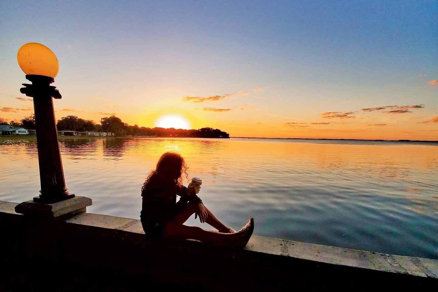 A woman sits at Ferran Park overlooking Lake Eustis at dusk. 