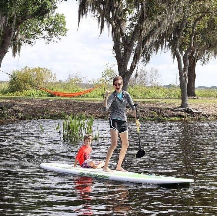 A woman paddleboards with her son.