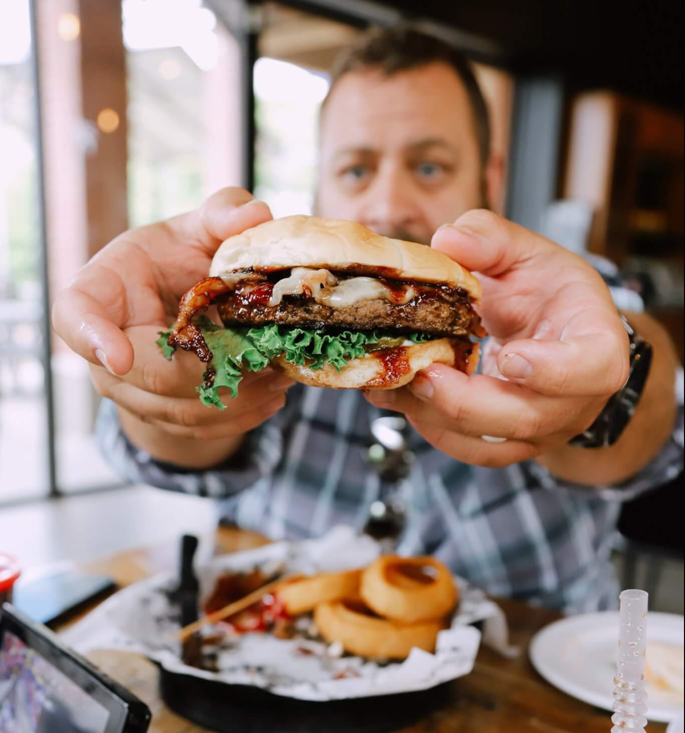 A man holds a hamburger up to the camera.
