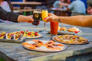 Two drinks cheersing with pizza and tacos under