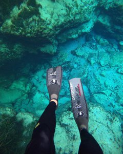 Underwater view of rocks at alexander springs, swim fins and legs in foreground